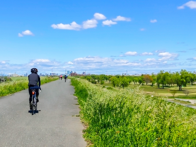 サイクリングロードを自転車で走る男性